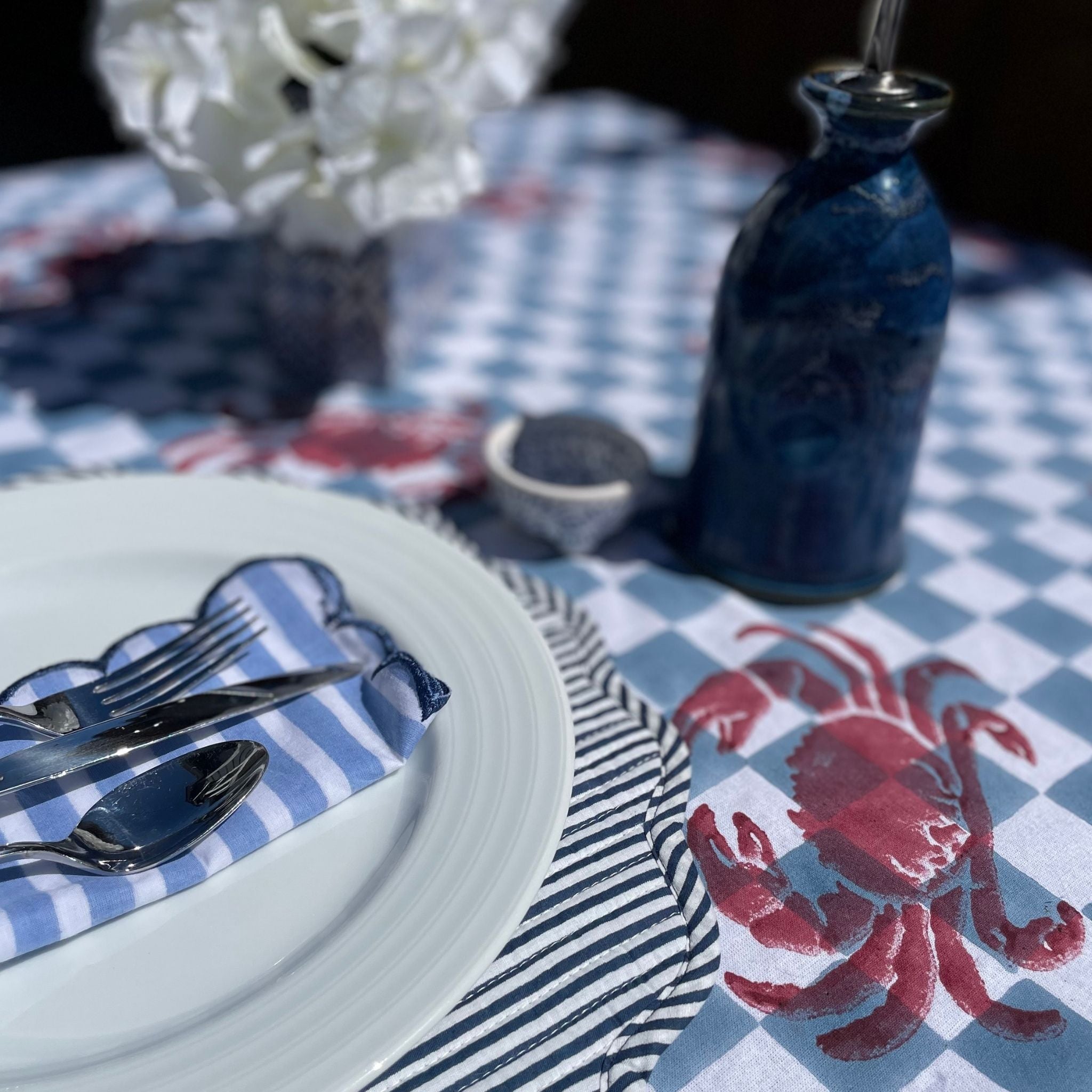 Blue and white tablescape with red crabs block printed on tablecloth.