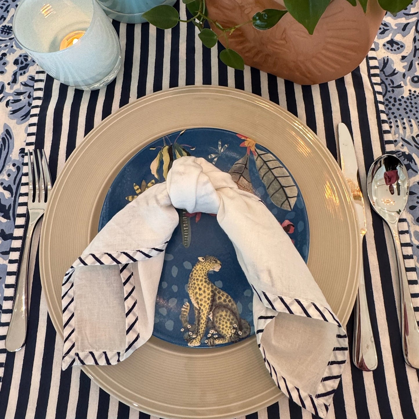 Elegant table setting with decorative plate and napkin on striped tablecloth.