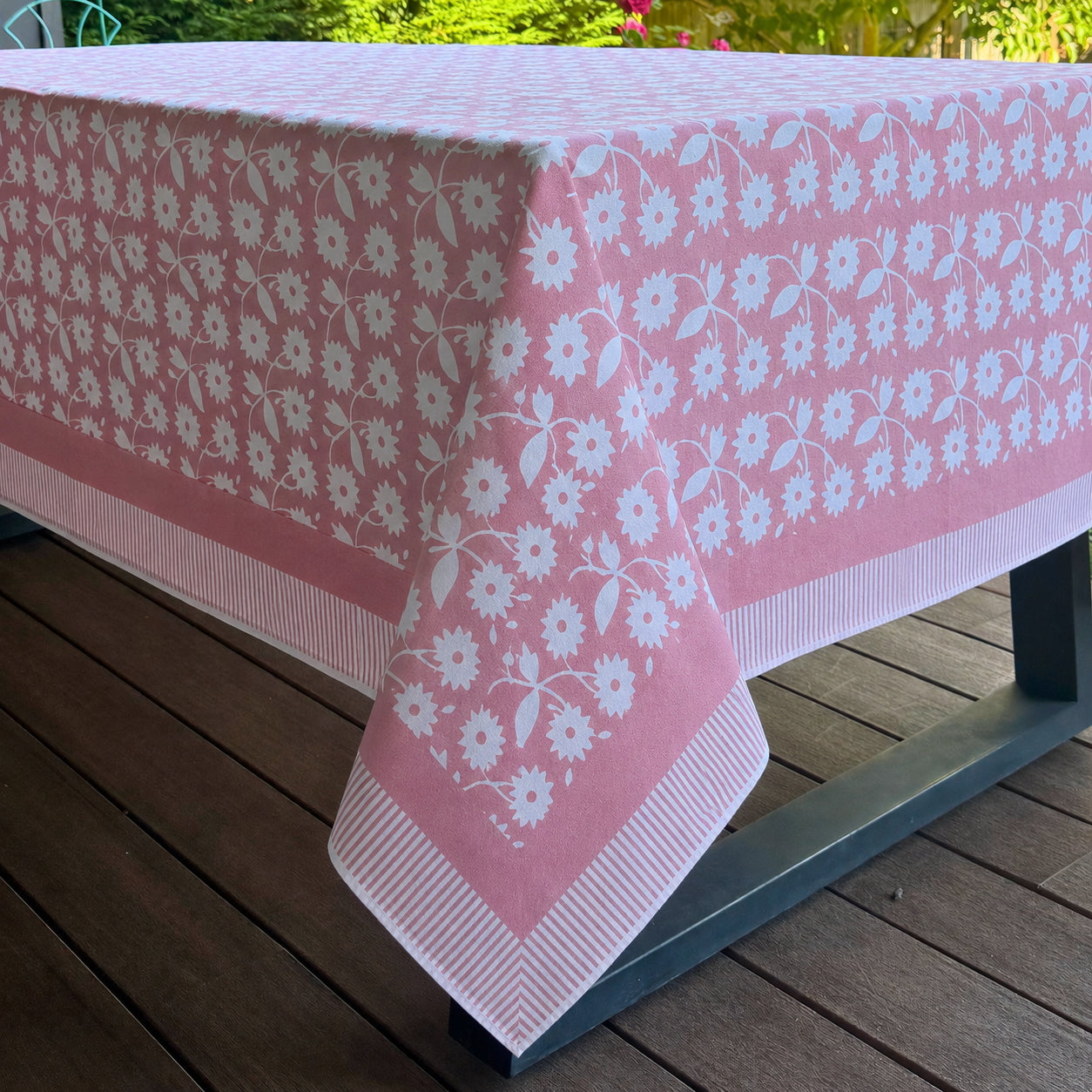 Pink floral tablecloth on a wooden table outdoors