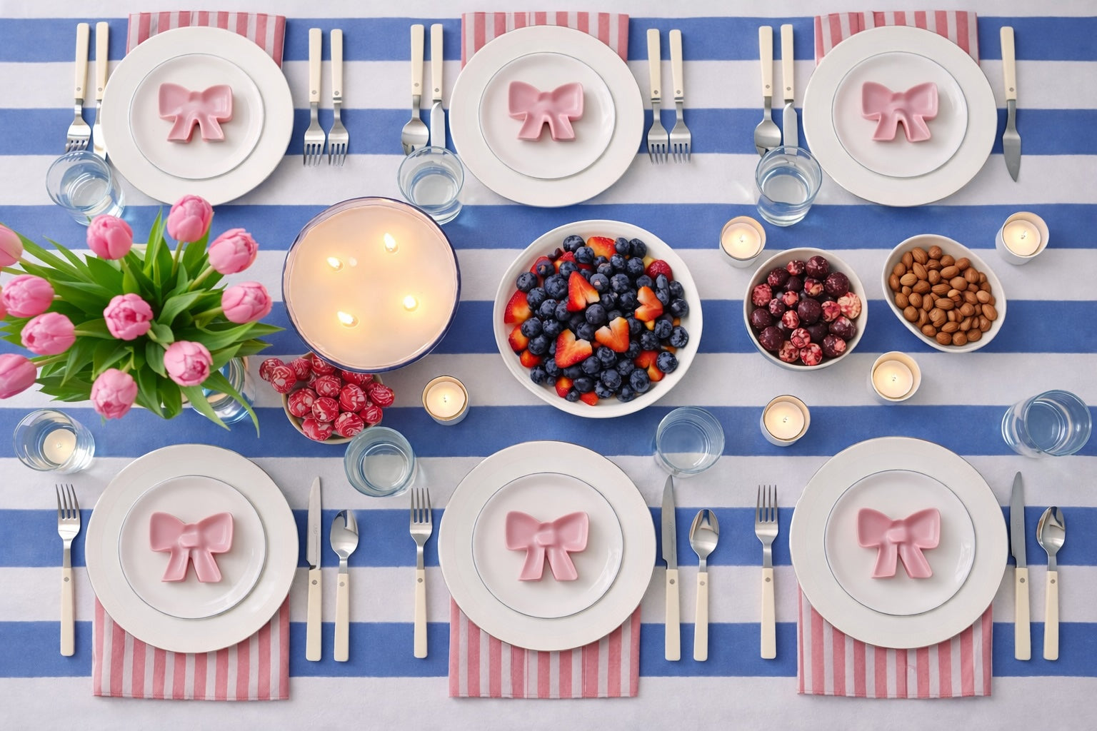Table set for Valentines Day meal with blue and white tablecloth and pink and white napkins from Quincy & Coco brand